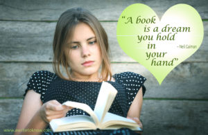 A girl reflects as she holds a book, with text that says “A Book is a Dream You Hold in Your Hand”